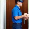 Coursier récupérant un colis devant une porte d’entrée.